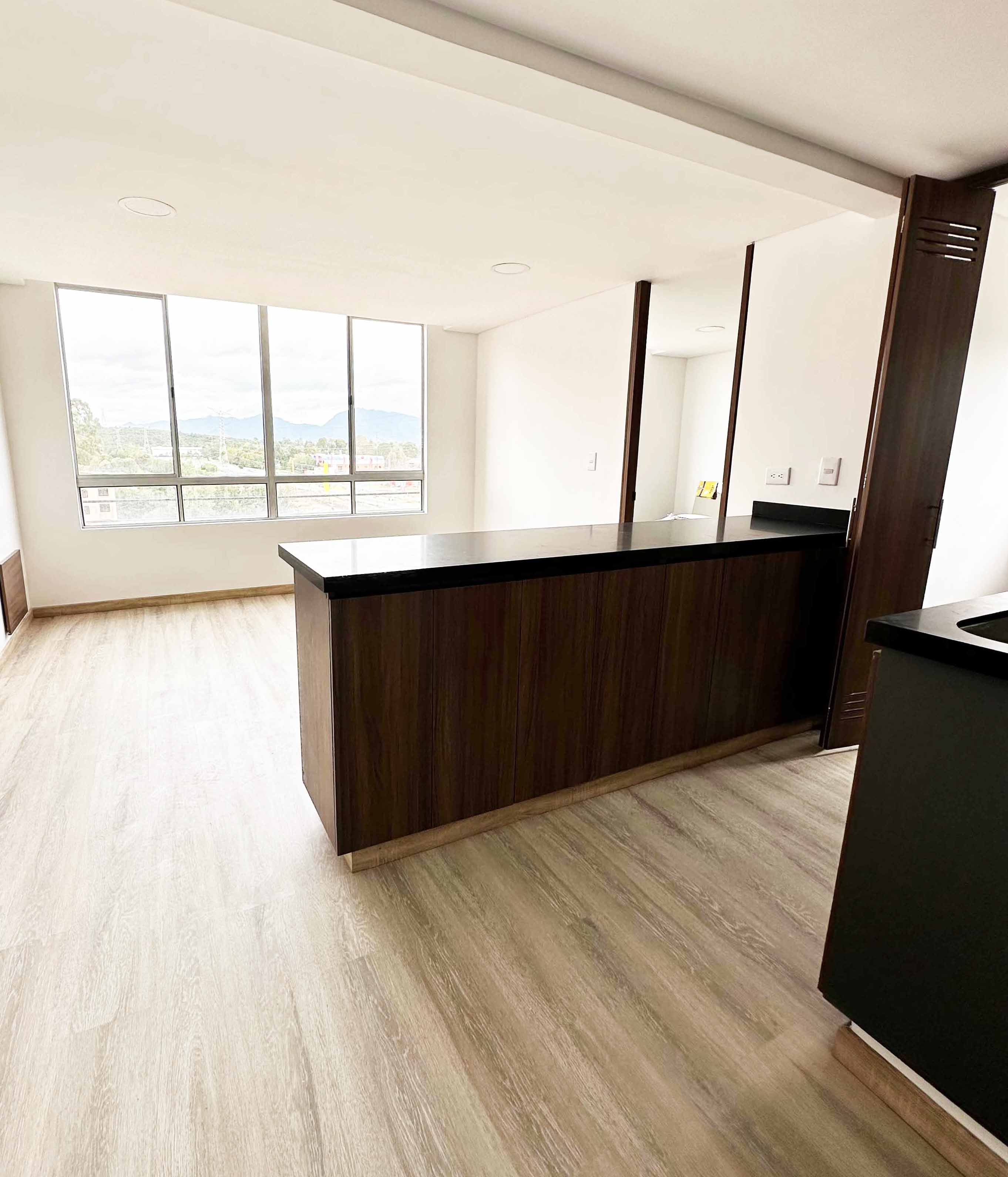 Sala amplia con ventanal y acabados neutros - diseño interior funcional para vivienda en Colombia