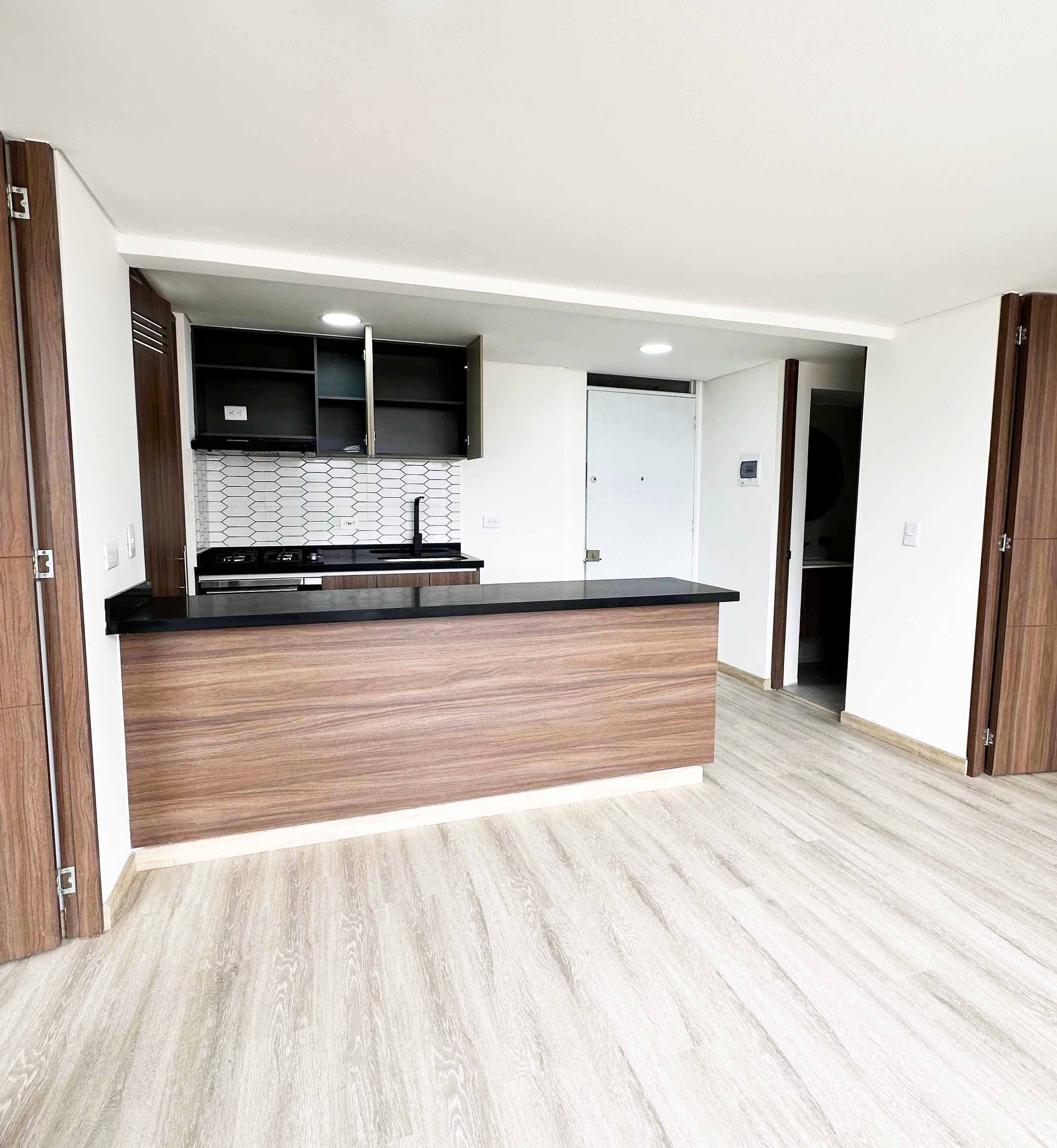 Sala con cocina abierta y acabados modernos en apartamento Colombia - espacios integrados con iluminación natural